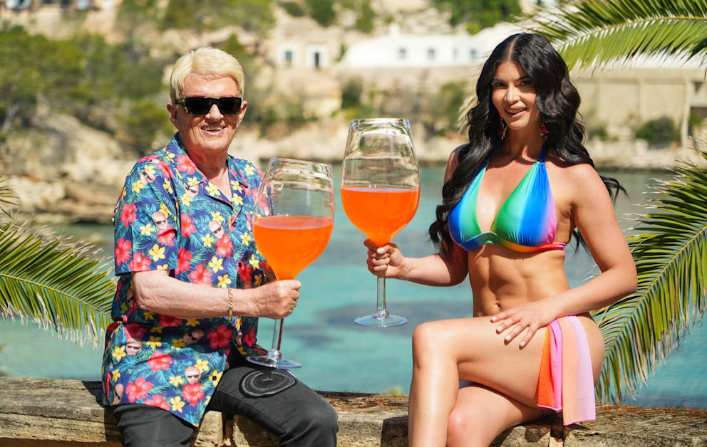 Unter der Sonne Mallorcas genießen Heino im Hawaii-Hemd und Micaela Schäfer im bunten Bikini ihren Aperol aus riesigen Gläsern