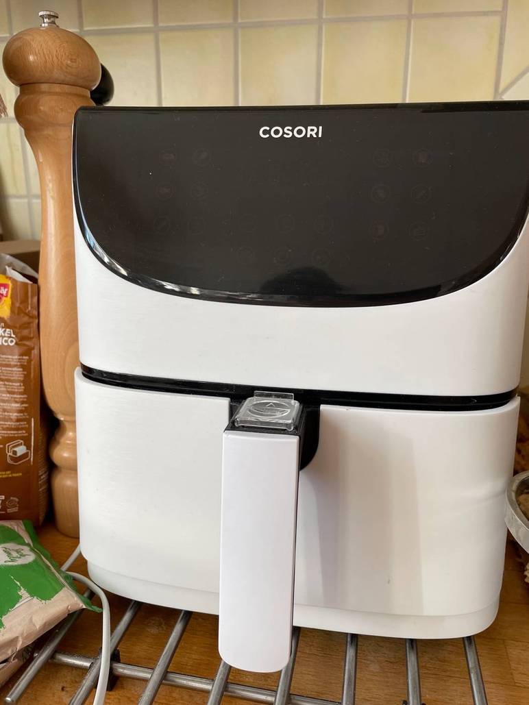 Nahaufnahme von vorn einer getesteten Heißluftfritteuse von COSORI im weißen Design, ausgeschaltet in einem Küchenambiente.