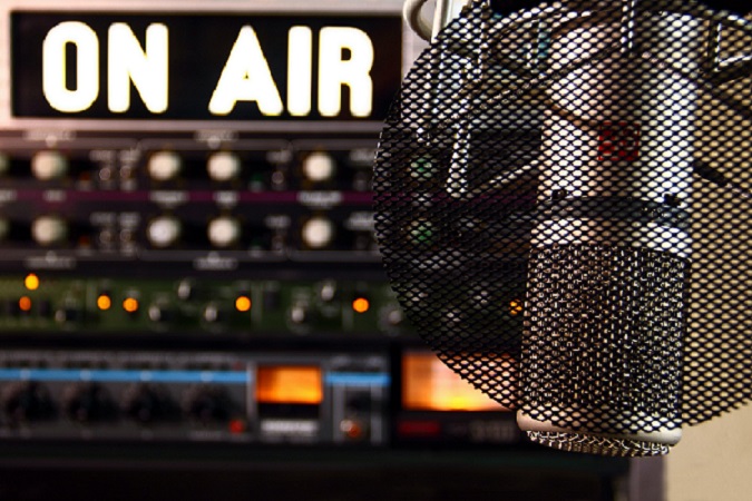 Radiomikrofon, im Hintergrund Lämpchen und schalter mit "On Air" Schriftzug